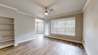This well-appointed single-floor residence combines modern design with functional living spaces throughout. The kitchen serves as a standout feature, showcasing a two-tone cabinet scheme with crisp white upper cabinets and warm taupe lower cabinets, complemented by sleek white quartz countertops and a decorative arabesque tile backsplash. Stainless steel appliances, including a range, over-the-range microwave, dishwasher, and refrigerator, complete the kitchen's contemporary aesthetic. Wood-look plank flooring flows consistently throughout the residence, adding warmth and visual continuity.

An open-concept layout connects the kitchen to the dining and living areas via a peninsula with bar seating, allowing natural light to circulate freely. The living and bedroom spaces feature crown molding, neutral gray walls, and ceiling fans, while large windows with blinds invite ample natural light. The bedroom is generously sized and leads to a well-organized walk-in closet outfitted with wire shelving systems for versatile storage.

The bathroom is thoughtfully designed with a dark-toned vanity, white countertop, a large framed mirror, and wood-look tile flooring, maintaining the cohesive aesthetic found throughout the residence. Overall, the space presents a clean, modern ambiance with quality finishes at every turn.