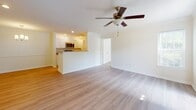 Located at 4911 Signature Dr in Myrtle Beach, SC, this single-floor community clubhouse showcases a thoughtfully designed coastal aesthetic throughout. The entrance welcomes visitors with a tray ceiling accented in muted teal, a striking coral-branch chandelier with a gold finish, warm hardwood flooring, and a patterned navy area rug — setting an inviting tone from the moment you step inside.

The main lounge is an expansive, light-filled gathering space defined by soaring tray ceilings painted in a soft sage green, dual ceiling fans, and generous arched windows paired with French doors that flood the room with natural light and outdoor views. Comfortable seating arrangements, coastal-themed décor, and decorative columns add architectural character to the space.

A dining nook adjacent to the lounge features a round white pedestal table surrounded by wicker chairs beneath an elegant arched window. The supporting kitchen area offers teal cabinetry, stainless steel appliances, and hardwood flooring, complemented by nautical artwork.

A dedicated sitting area features bold blue textured wallpaper and curated coastal art, providing a relaxed retreat. The fitness center is well-appointed with treadmills, ellipticals, stationary bikes, free weights, medicine balls, wall-mounted televisions, and rubberized flooring — with a mirror wall and natural light enhancing the workout environment.