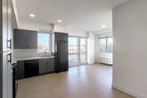 Located at 2358 Alum Rock Ave in San Jose, California, this modern two-bedroom, one-bathroom unit offers a well-designed layout across a single floor. Light wood-style flooring flows throughout, lending a clean, contemporary feel to every room.

The kitchen is a standout feature, outfitted with sleek gray shaker cabinetry extending to the ceiling for ample storage, white countertops, and a full suite of black appliances including a range, microwave, dishwasher, and refrigerator. Large windows and a sliding glass door flood the open kitchen and living area with natural light and provide views of the surrounding neighborhood.

Both bedrooms are bright and well-proportioned, each featuring windows that allow natural light and outdoor views. Wall-mounted PTAC units provide individual climate control. The primary bedroom is generously sized and includes access to a dedicated walk-in closet equipped with wire shelving for organized storage.

The bathroom is designed with accessibility in mind, featuring a roll-in shower with a fold-down bench and grab bars, a blue vanity with a white countertop, and a large mirror. The clean white finishes maintain a consistent, modern aesthetic throughout. Recessed lighting in the kitchen and living area completes this thoughtfully designed home.