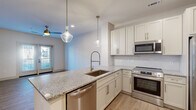 Located at 2145 Robin Lark Dr in Winston-Salem, NC, this well-appointed one-bedroom, one-bathroom residence offers a cohesive modern design throughout its efficiently laid-out single floor. Light wood-tone flooring flows seamlessly across all rooms, creating a warm and consistent aesthetic.

The kitchen is a standout feature, showcasing granite countertops, crisp white shaker cabinetry with brushed nickel hardware, a subway tile backsplash, and a full suite of stainless steel appliances including a French door refrigerator, electric range, built-in microwave, and dishwasher. A peninsula with an undermount sink and stylish pendant lighting above makes this kitchen both functional and visually striking.

The living area benefits from a ceiling fan and glass-panel doors that invite natural light and provide outdoor access. The bedroom is a comfortable retreat with large windows offering exterior views and its own ceiling fan. Two closets provide ample storage throughout the unit.

The bathroom features large-format marble-look tile in the tub/shower surround, complemented by granite vanity countertops and wood-tone flooring for a polished finish. A dedicated in-unit laundry space with stacked washer and dryer connections and overhead shelving adds everyday convenience to this well-rounded residence.