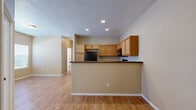 This two-story home offers a practical and well-organized layout across two floors, with the main living areas occupying the more spacious ground level. The kitchen is a functional centerpiece, featuring warm honey-toned cabinetry, dark granite-style countertops, black appliances including a refrigerator, gas range, and built-in microwave, and a peninsula with bar seating that opens to the adjacent living area. Light hardwood flooring runs throughout the main level, adding warmth and continuity to the space. Recessed lighting and a textured ceiling provide a clean, finished look overhead.

The upper floor houses the bedrooms, each carpeted for comfort and finished in neutral tones. The primary bedroom offers a generous footprint with a row of high clerestory windows that bring in natural light while maintaining privacy. The additional bedrooms are well-sized and include sliding closets with built-in rod storage. A shared full bathroom on the upper level features a granite-topped vanity, tiled tub-shower combination, and a window for natural ventilation.

A dedicated laundry room with hardwood flooring and wall-mounted shelving accommodates a full-size washer and dryer. Two staircase access points contribute to the home's efficient flow between floors.