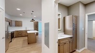 Located at 34040 W 90th St in De Soto, Kansas, this thoughtfully designed 2-bedroom, 3-bathroom home offers a clean, modern aesthetic throughout its single-floor layout. The open-concept kitchen and living area serves as the heart of the home, showcasing light hardwood-style flooring, recessed lighting, and a seamless flow between spaces. The kitchen is a standout feature, equipped with stainless steel appliances including a refrigerator, range, microwave, and dishwasher, complemented by warm-toned shaker cabinetry, white countertops, a central island with pendant lighting, and a sink with a view into the room. The living area is bright and airy, with a bank of windows inviting generous natural light and a door providing direct outdoor access. The primary bedroom is generously sized, featuring plush carpeting, a ceiling fan, large windows, and its own exterior door. The second bedroom is equally comfortable with carpet flooring, a window, and access to a walk-in closet. The bathrooms are well-finished, with one featuring a tiled walk-in shower and wood-look flooring, and another with warm cabinetry, white countertops, and an illuminated mirror. Two closets add practical storage throughout this move-in-ready home.