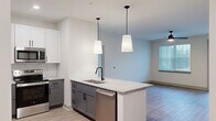 Located at 1130 Annondale Dr in Fayetteville, NC, this well-designed single-story residence offers 2 bedrooms and 2 bathrooms with a thoughtful, functional layout. The open-concept kitchen and living area serves as the heart of the home, highlighted by a central island with a granite countertop, dual pendant lights, and a stainless steel sink with a matte black faucet. The kitchen features two-tone cabinetry — white upper cabinets paired with gray lower cabinets — complemented by a white subway tile backsplash and a full suite of stainless steel appliances. Wood-look flooring runs consistently throughout the entire residence, creating a cohesive and contemporary feel. The living area is bright and airy, with natural light streaming in through large windows fitted with blinds, a ceiling fan, and access to an exterior door. Both bedrooms are comfortably sized, each with ceiling fans and natural light; the primary bedroom leads directly to a walk-in closet outfitted with built-in wire shelving on three walls. The bathrooms are finished with granite-top white vanities, matte black hardware, and a tub-shower combination. A connecting hallway efficiently links the bedrooms, closets, and bathrooms, completing this clean and modern home.