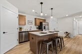 This well-appointed 1,040 sq ft second-floor condo in Mukwonago, WI offers 2 bedrooms, 2 bathrooms, and a thoughtfully designed single-level layout. The kitchen is a standout feature, boasting warm honey-toned cabinetry, white quartz countertops, a central island with pendant lighting, stainless steel appliances including a refrigerator with ice maker, microwave, range, and dishwasher, and light hardwood-style flooring. The adjacent living room is bright and airy, featuring sliding glass doors that open to a private balcony with neighborhood views. Both bedrooms are carpeted and filled with natural light; the 170 sq ft primary bedroom includes an en suite bathroom, while the second bedroom offers a spacious closet with sliding doors. Each bathroom is finished with warm wood vanity cabinetry, white countertops, large mirrors, stylish light fixtures, and hardwood-style flooring. The primary bath includes a glass-enclosed shower/tub combo. The unit also features two closets for additional storage. Clean neutral tones and consistent finishes throughout create a cohesive, move-in-ready atmosphere.