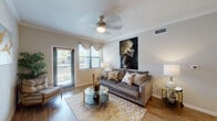 This well-designed single-floor residence showcases a cohesive blend of modern style and everyday comfort across its thoughtfully arranged spaces. The living room serves as the heart of the home, featuring warm hardwood-style flooring, crown molding, and a ceiling fan overhead. Natural light pours in through large windows dressed with elegant valances, while a sliding glass door opens to a private balcony, extending the living space outdoors. A bold statement artwork anchors the room, adding a sophisticated artistic touch.

Adjacent to the living area, the dining space offers an intimate setting highlighted by a rich wood dining table and a striking multi-panel gold abstract art arrangement on the wall. A convenient closet nearby provides additional storage.

The kitchen is both functional and stylish, outfitted with dark espresso cabinetry, granite countertops, and black appliances including a refrigerator, range, and built-in microwave. Hardwood-style flooring continues throughout, tying the spaces together seamlessly.

The bedroom is a serene retreat featuring plush carpeting, multiple windows that invite natural light and outdoor views, and a ceiling fan for year-round comfort. The bathroom is finished with dark wood cabinetry, granite countertops, a large vanity mirror, and light tile flooring, offering a clean and refined aesthetic.