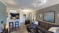 This single-story residence offers a thoughtfully designed open-concept layout that seamlessly connects the living, dining, and kitchen areas. The living room features rich wood-look flooring, crown molding, and a neutral color palette accented by a warm taupe feature wall, creating a welcoming and cohesive atmosphere. Track lighting overhead adds a modern touch, while the space flows naturally into a compact dining area and the kitchen beyond.

The kitchen is equipped with dark espresso cabinetry, granite-style countertops, stainless steel appliances including a refrigerator, range, and microwave, and a teal accent wall that adds a vibrant pop of color. A breakfast bar provides additional seating and visual separation from the living space. An in-unit washer and dryer are conveniently located nearby.

The primary bedroom offers plush carpeting, a walk-in closet, and direct access to a full bathroom with a single vanity and a soaking tub with shower combination. The second bedroom is equally spacious with a walk-in closet, carpet flooring, and ample natural light from large windows.

A dedicated home office features wood-look floors, dual windows with outdoor views, a ceiling fan, and a built-in desk with upper cabinetry. A second full bathroom with dark vanity cabinetry and a tub-shower combination serves the remaining rooms. Hallway storage provides additional organizational utility throughout.