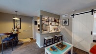 This single-floor residence offers a thoughtfully designed layout that blends modern style with everyday functionality. The living room serves as a welcoming focal point, highlighted by a stone-surround corner fireplace, rich hardwood-style flooring, and a sliding glass door that fills the space with natural light and provides access to an outdoor area with views of surrounding greenery.

The kitchen is a standout feature, showcasing an industrial-inspired design with black pipe open shelving, a granite-style countertop peninsula, and bar seating for casual dining. Stainless steel appliances, track lighting, and a sleek layout make this kitchen both practical and visually striking. Adjacent to the kitchen, a cozy dining nook with a sliding glass door creates an intimate setting for meals.

The primary bedroom is generously proportioned, featuring a ceiling fan, plush carpeting, multiple windows that allow abundant natural light, and a walk-in closet. The second bedroom is equally comfortable, also with carpet flooring, a ceiling fan, and convenient access to a stacked in-unit washer and dryer. A well-appointed bathroom with a framed mirror, granite-style countertop, and stylish cabinetry completes this inviting home.