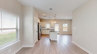 Located at 7711 Longmire Rd in Conroe, TX, this thoughtfully designed single-story home offers a well-organized layout encompassing one bedroom, two bathrooms, a dedicated laundry room, and a closet. Light-toned luxury vinyl plank flooring flows throughout, creating a cohesive and easy-to-maintain aesthetic.

The open-concept kitchen and living area serves as the heart of the home. The kitchen is outfitted with crisp white cabinetry, dark granite countertops, a subway tile backsplash, stainless steel appliances — including a refrigerator, range, microwave, and dishwasher — and a central island with pendant lighting above. The adjoining living area is bright and airy, benefiting from multiple windows with blinds and a ceiling fan, which also appears in the bedroom.

The spacious primary bedroom features natural light from dual windows with outdoor views and direct access to the closet. The two bathrooms are finished with granite countertops, white cabinetry, and matte black fixtures; one includes a full tub-shower combination with white tile surround.

The dedicated laundry room accommodates a full-size washer and dryer with overhead shelving. A doll house view reveals the home also includes an outdoor area with a fenced patio space and green turf.