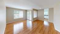 This single-floor residence is defined by warm hardwood flooring that flows consistently throughout, complementing the neutral, beige-toned walls and crisp white trim found in every room. The spacious living area is a standout feature, bathed in natural light from large windows and a sliding glass door that opens to a private balcony, creating a seamless connection to the outdoors. An arched accent window in one of the rooms adds a subtle architectural detail that enhances the overall character of the space.

The kitchen is thoughtfully designed with white shaker-style cabinetry, granite countertops, and a full suite of stainless steel appliances including a refrigerator, range, and dishwasher. A window above the sink allows for natural light and ventilation, making the space both functional and inviting.

The bedroom features generous proportions and direct access to a walk-in closet outfitted with wire shelving units, offering substantial and organized storage. The full bathroom is well-appointed with a granite-topped white vanity, an undermount sink with brushed nickel fixtures, a tiled shower-tub combination, and a large mirror. Clean white walls and hardwood floors carry through into the bathroom, maintaining the cohesive aesthetic of the entire unit.