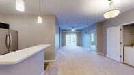 Located at 2395 N Forest Rd in Getzville, NY, this 2-bedroom, 2-bathroom residence offers a thoughtfully designed single-floor layout. The open-concept living, dining, and kitchen area serves as the heart of the home, featuring plush wall-to-wall carpeting, a ceiling fan, and sliding glass doors that invite natural light and outdoor views. The kitchen is equipped with stainless steel appliances, including a French door refrigerator, and is accented by pendant lighting and a breakfast bar that connects seamlessly to the living and dining space. The generously sized primary bedroom features carpeted flooring, a large closet, and its own private bathroom complete with dark-cabinetry vanity, wood-look tile flooring, and a walk-in closet. The second bedroom is carpeted and bright, with a window overlooking the exterior. The second bathroom mirrors the refined aesthetic with a dark vanity, white countertop, and wood-look tile flooring. Additional highlights include a utility room with in-unit laundry, two closets for ample storage, and a neutral color palette throughout that creates a clean, cohesive ambiance. The overall design balances comfort and functionality in a well-organized floor plan.