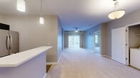 Located at 2395 N Forest Rd in Getzville, NY, this 2-bedroom, 2-bathroom residence offers a thoughtfully designed single-floor layout. The open-concept living, dining, and kitchen area serves as the heart of the home, featuring plush wall-to-wall carpeting, a ceiling fan, and sliding glass doors that invite natural light and outdoor views. The kitchen is equipped with stainless steel appliances, including a French door refrigerator, and is accented by pendant lighting and a breakfast bar that connects seamlessly to the living and dining space. The generously sized primary bedroom features carpeted flooring, a large closet, and its own private bathroom complete with dark-cabinetry vanity, wood-look tile flooring, and a walk-in closet. The second bedroom is carpeted and bright, with a window overlooking the exterior. The second bathroom mirrors the refined aesthetic with a dark vanity, white countertop, and wood-look tile flooring. Additional highlights include a utility room with in-unit laundry, two closets for ample storage, and a neutral color palette throughout that creates a clean, cohesive ambiance. The overall design balances comfort and functionality in a well-organized floor plan.