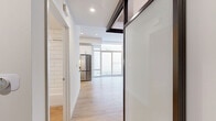 Located at 1810 State Street in San Diego's vibrant 92101 corridor, this contemporary unit on the seventh floor offers a thoughtfully designed single-level layout. Light wood-tone flooring runs throughout the entire space, creating a warm and cohesive aesthetic that complements the crisp white walls and recessed lighting overhead.

The open-concept kitchen is a standout feature, outfitted with white shaker cabinetry, dark countertops, a classic white subway tile backsplash, and a full suite of stainless steel appliances including a refrigerator, gas range, and microwave. Under-cabinet lighting adds both function and ambiance to the cooking space.

The main living area is bright and airy, benefiting from floor-to-ceiling sliding glass doors that flood the interior with natural light and provide access to an outdoor space. A mirrored sliding closet in the sleeping area enhances the sense of openness while maximizing storage.

The bathroom is cleanly appointed with a white vanity, framed mirror, pendant lighting, and a tiled tub-shower combination, maintaining the modern and minimal aesthetic found throughout the unit.

Dark-framed glass partition elements add an architectural detail that defines spaces without sacrificing the open feel. Overall, the unit presents a modern, move-in-ready environment with efficient use of its compact footprint.