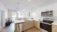 This single-floor residence offers a thoughtfully designed layout that blends modern aesthetics with functional living. The open-concept kitchen serves as the heart of the space, featuring warm wood-tone lower cabinetry paired with crisp white upper cabinets and a classic subway tile backsplash. Light quartz countertops extend across the L-shaped layout, offering generous prep space. A full suite of stainless steel Whirlpool appliances — including a refrigerator, electric range, over-the-range microwave, and dishwasher — ensures everyday convenience. Pendant lighting hangs above the peninsula, adding a polished touch while illuminating the workspace. Wood-look flooring flows throughout the main living areas, contributing warmth and continuity.

The bedrooms are carpeted for comfort and feature neutral walls, ceiling fans, and windows that invite natural light. The bathroom maintains the design language of the kitchen, showcasing a wood-tone vanity with a white countertop, a large mirror, and hardwood-style flooring. A tall storage cabinet provides additional organization, while a decorative living plant wall adds a distinctive and refreshing accent. Overall, the space presents a clean, contemporary aesthetic with cohesive finishes throughout.