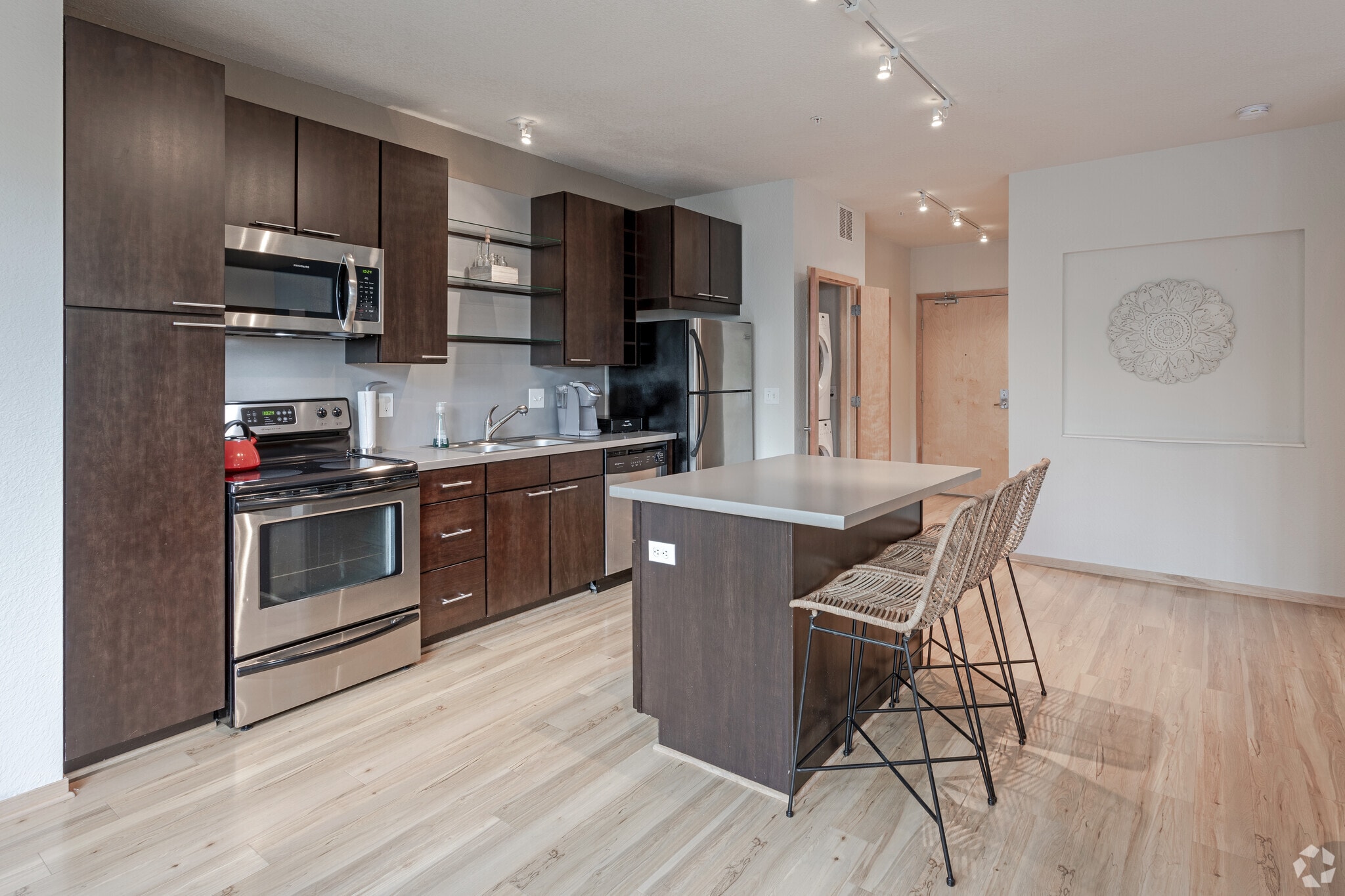 Modern kitchen with stainless steel appliances, dark wood cabinets, and a large island with seating.