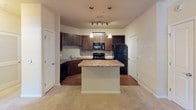 Located at 601 Sleepy Hollow Rd in Charlotte, NC, this single-story residence offers a well-organized layout with a cohesive design throughout. The kitchen serves as a central highlight, featuring rich dark-stained cabinetry, granite-style countertops, a tile backsplash, and black appliances including a range, over-the-range microwave, dishwasher, and refrigerator. A peninsula island with pendant lighting overhead provides additional prep space and casual seating potential, while wood-look flooring grounds the area with warmth. A built-in wine rack adds a practical decorative touch.

The living area is generously proportioned, finished with neutral carpeting and crown molding that lends a polished architectural detail. Natural light enters through sliding glass doors that open onto a private balcony overlooking lush greenery, creating a pleasant indoor-outdoor connection. The bedroom is comfortably sized, carpeted, and equipped with a ceiling fan and a window with outdoor views, contributing to a bright and airy feel.

The bathroom is cleanly appointed with a tub-shower combination featuring tiled surrounds, a dark-vanity cabinet with granite-style countertop, a single undermount sink, and tile flooring. Overall, the space maintains a consistent, functional aesthetic throughout.