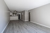Located at 2800 E Tahquitz Canyon Way in Palm Springs, California, this single-story unit offers a clean, updated interior with a cohesive neutral color palette and light wood-look flooring throughout. The open living area is spacious and airy, anchored by a ceiling fan and a textured ceiling. A half-wall with beadboard paneling separates the living space from the kitchen, providing an open yet defined layout.

The kitchen is well-appointed with white cabinetry, granite-style countertops, a stainless steel double-basin sink, and a black dishwasher. A window above the sink frames views of surrounding palm trees and the surrounding landscape, bringing in natural light and a connection to Palm Springs' iconic scenery.

The bedrooms are generously sized with large windows that invite abundant natural light and views of mature trees. Each bedroom features sliding closet doors with built-in shelving and hanging rods, offering practical storage solutions. One bedroom includes dual closets for added convenience.

The bathroom is neatly finished with a full tub-and-shower combination, a dark granite-topped vanity with white cabinetry, and wood-look flooring. Throughout the unit, clean white baseboards and warm taupe walls create a bright, welcoming ambiance suited to Palm Springs living.