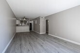 Located at 2800 E Tahquitz Canyon Way in Palm Springs, California, this single-story unit offers a clean, updated interior with a cohesive neutral color palette and light wood-look flooring throughout. The open living area is spacious and airy, anchored by a ceiling fan and a textured ceiling. A half-wall with beadboard paneling separates the living space from the kitchen, providing an open yet defined layout.

The kitchen is well-appointed with white cabinetry, granite-style countertops, a stainless steel double-basin sink, and a black dishwasher. A window above the sink frames views of surrounding palm trees and the surrounding landscape, bringing in natural light and a connection to Palm Springs' iconic scenery.

The bedrooms are generously sized with large windows that invite abundant natural light and views of mature trees. Each bedroom features sliding closet doors with built-in shelving and hanging rods, offering practical storage solutions. One bedroom includes dual closets for added convenience.

The bathroom is neatly finished with a full tub-and-shower combination, a dark granite-topped vanity with white cabinetry, and wood-look flooring. Throughout the unit, clean white baseboards and warm taupe walls create a bright, welcoming ambiance suited to Palm Springs living.