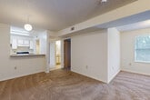 Located at 1700 Kenyon Circle in Kissimmee, Florida, this single-floor, 3-bedroom, 2-bathroom residence offers a functional and well-organized layout. The interior is finished with neutral white walls throughout, with carpeted flooring in the living and bedroom areas and tile flooring in the entry corridor and bathrooms. The open-concept living, dining, and kitchen area forms the heart of the home, featuring a breakfast bar peninsula, white cabinetry, and a textured ceiling. A pendant light fixture anchors the dining space, while the living room provides generous room for furnishings. A central hallway connects the bedrooms and bathrooms, with a utility panel and HVAC vents visible along the corridor. Each of the three bedrooms offers carpeted floors and windows that bring in natural light, with the primary bedroom providing a comfortable amount of space and closet access. Three dedicated closets serve the unit's storage needs. Both bathrooms include tub-shower combinations with white tile surrounds, vanities with countertops, and tile flooring. A dedicated laundry area adds everyday convenience. The overall ambiance is clean, bright, and move-in ready, suited for a range of living arrangements.