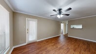 This one-bedroom, one-bathroom unit at 2801 Walnut Bend Ln in Houston, Texas offers a practical and comfortable single-floor layout. The open living area greets you with warm wood-style flooring, neutral beige walls, crown molding, and a ceiling fan with built-in light fixture. A private entry door with a sidelight window allows natural light to filter in, contributing to a bright and welcoming atmosphere. The combined kitchen and living space flows seamlessly, with the galley-style kitchen featuring white cabinetry, granite-look countertops, a double sink, an electric range, a dishwasher, and a full-size refrigerator — providing ample functionality in a well-organized layout. A hallway connects the main living area to the private bedroom and bathroom. The spacious bedroom is finished with plush carpet, a ceiling fan with lighting, and a generously sized window overlooking mature trees, offering a peaceful outdoor view. A dedicated closet provides convenient storage. The full bathroom includes a granite-look vanity with white cabinetry, a large mirror, and a tiled shower/tub combo. Wood-style flooring runs through the main living spaces, creating a cohesive and easy-to-maintain interior throughout this efficiently designed home.