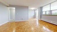 Located at 981 Main St W in Hamilton, Ontario, this well-laid-out unit offers 3 bedrooms, 2 bathrooms, and a thoughtfully organized single-floor plan. The entrance leads into a galley-style kitchen finished with white cabinetry, tile flooring, and a window that draws in natural light, providing a clean and functional cooking space. Adjacent to the kitchen, the spacious living room is a standout feature, boasting classic parquet wood flooring in a warm honey tone, large floor-to-ceiling windows, and baseboard heating — creating a bright and welcoming atmosphere with ample room for both living and dining arrangements. The three bedrooms each continue the parquet flooring theme and are finished with soft grey walls, offering a calm and neutral palette. The primary bedroom provides a generous footprint and includes access to a closet. The secondary bedrooms are well-proportioned, each featuring windows that invite natural light and outdoor views. The two bathrooms are finished with clean white tile, including a full bathroom with a soaking tub and a second bathroom with a pedestal sink and mirrored cabinet. The overall design is practical and consistent, with uniform flooring and neutral tones throughout.