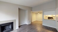 This single-floor residence offers a thoughtfully designed layout with a neutral color palette and a blend of hardwood-style and carpeted flooring throughout. The living area serves as the heart of the home, featuring a tile-surround fireplace, vaulted ceilings, and a sliding glass door that invites natural light and provides outdoor access. A ceiling fan in the adjoining dining or flex space adds both function and comfort, while a dedicated alcove creates a natural room division.

The galley-style kitchen is efficiently organized with white shaker cabinetry, sleek brushed-nickel hardware, stone-toned countertops, and a full suite of black appliances including a range, refrigerator, and dishwasher. An overhead range hood and flush-mount lighting complete the practical setup.

The bedrooms feature plush carpeting and generous proportions, with one bedroom offering direct access to a bathroom vanity area. The bathrooms are finished with stone-toned countertops, undermount sinks, and large mirrors. A hallway bathroom conveniently houses an in-unit washer and dryer behind bi-fold doors. A separate water closet provides additional privacy. Clean white trim and understated finishes throughout lend the space a modern, move-in-ready appeal.