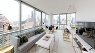 This high-rise residence is defined by its expansive floor-to-ceiling windows, which frame sweeping panoramic views of the city skyline and surrounding urban landscape, flooding the interior with abundant natural light throughout the day. The open-concept living and dining area serves as the heart of the home, where light hardwood-style flooring, crisp white walls, and a seamless layout create a bright, contemporary atmosphere. A sleek kitchen features stainless steel appliances, two-tone cabinetry combining white upper cabinets with wood-grain lower units, a white subway tile backsplash, and light quartz countertops. The living space connects fluidly to the dining area, both oriented to take full advantage of the striking cityscape beyond the glass. Two well-proportioned bedrooms each offer a serene retreat; one enjoys direct floor-to-ceiling window views of the skyline, while both feature clean lines, ample closet space, and light, neutral finishes. Two bathrooms are finished in a consistent modern palette, with wood-grain floating vanities, white quartz countertops, large-format tile, and a soaking tub with shower combination in the primary bath. The overall ambiance is polished, airy, and urban.