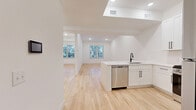 Located at 325-327 Union Blvd in Totowa, NJ, this thoughtfully designed one-bedroom, one-bathroom unit offers a clean, modern aesthetic with high-quality finishes throughout. The open-concept layout seamlessly connects the kitchen and living area, creating a bright and airy atmosphere enhanced by recessed lighting and light-toned hardwood floors that extend throughout the space.

The kitchen is a standout feature, outfitted with crisp white shaker cabinetry, sleek quartz countertops, a matte black faucet, and a full suite of stainless steel appliances including a gas range, built-in microwave, dishwasher, and refrigerator. A peninsula provides additional prep and serving space while maintaining the open flow into the living area, which benefits from natural light through multiple windows with views of surrounding greenery.

The bedroom is a well-proportioned, serene retreat with hardwood flooring, a window overlooking lush outdoor scenery, and a private walk-in closet equipped with built-in shelving and hanging rods for generous storage. The bathroom is finished with large-format gray tile flooring, white shaker vanity cabinetry, a quartz countertop, a large mirror, and a tub-shower combination enclosed by a sliding glass barn-style door with built-in shelving. Clean white walls and matte black fixtures tie the design together throughout the entire unit.