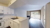 Located at 3190 Oak Rd in Walnut Creek, CA, this single-floor residence offers a thoughtfully designed layout that balances functionality with a clean, updated aesthetic. The open-concept kitchen flows seamlessly into the living area, creating a connected and spacious feel. The kitchen is well-appointed with white shaker-style cabinetry, a subway tile backsplash, marble-look quartz countertops, a double-basin stainless steel sink, and a full suite of white appliances including a gas range, over-the-range microwave, dishwasher, and a side-by-side refrigerator. Dark hardwood-style flooring runs throughout the main living areas, providing a warm contrast to the light-toned walls and cabinetry.

The living room features a fireplace with a classic mantel as a focal point, set against warm taupe-toned walls. Sliding glass doors open to an outdoor area, filling the space with natural light and providing views of surrounding greenery. A carpeted bedroom also benefits from its own set of sliding glass doors, offering additional outdoor access and natural light.

The bathroom is finished with wood-style flooring, white cabinetry, a single vanity, and a shower-tub combination enclosed by sliding glass doors, maintaining a clean and cohesive design throughout.