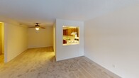 Located at 10111 Cedar Lake Rd in Minnetonka, Minnesota, this single-floor unit offers a practical and comfortable layout designed for everyday living. The living area is generously proportioned, featuring neutral carpet flooring, a textured ceiling, and baseboard heating running along the perimeter walls. A sliding glass door opens directly onto a private balcony, allowing natural light to filter in while providing pleasant views of surrounding trees. A wall-mounted air conditioning unit ensures year-round climate comfort.

A distinctive pass-through window connects the living area to the kitchen, creating an open feel while maintaining defined spaces. The kitchen is outfitted with rich, dark oak cabinetry offering substantial upper and lower storage, light countertops, a double stainless steel sink, a white refrigerator, and a range. Tile flooring completes the kitchen's functional design.

The bedroom is well-sized and features dual sets of louvered bi-fold closet doors flanking a central hallway entry, providing exceptional storage capacity. A separate carpeted room with its own window offers additional flexible living space.

The bathroom includes white tile flooring, a full tub-shower combination with white tile surround, a vanity with storage, and a recessed ceiling light, presenting a clean and straightforward design throughout.