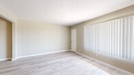 This single-floor unit offers a clean, functional layout designed for comfortable everyday living. The living area is a standout feature, showcasing light wood-style laminate flooring that extends throughout the space, complemented by neutral beige walls and crisp white baseboards. Large windows dressed with vertical blinds allow natural light to fill the room, creating a bright and airy atmosphere. A solid entry door provides a welcoming and secure point of access.

The kitchen is efficiently designed, featuring white upper and lower cabinetry that offers ample storage, a double-basin stainless steel sink, and a light countertop workspace. Black appliances, including a gas range and refrigerator, add a practical contrast to the white cabinetry, while a ceiling-mounted light fixture ensures the space is well illuminated.

The bathroom is finished with neutral large-format wall tiles surrounding the shower and tub combination, a white vanity with an integrated sink, a mirror with an attached towel bar, and standard fixtures throughout — providing a tidy and utilitarian space.

The 3D model reveals a well-organized single-level floor plan with clearly defined living, kitchen, and private areas, making efficient use of the available footprint. Overall, the unit presents a tidy, move-in-ready space with consistent finishes throughout.