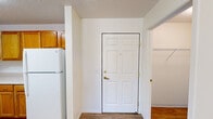 This single-floor residence offers a practical and comfortable layout across two bedrooms and three bathrooms. The entry foyer opens directly to the kitchen and living area, where warm honey-toned wood cabinetry, white appliances including a refrigerator, electric range, and built-in microwave, and light hardwood-style flooring define a functional kitchen space. The adjacent living room features soft carpet flooring and a sliding glass door that invites natural light into the space.

The generously sized primary bedroom features plush carpeting and connects to a well-equipped bathroom boasting a wide vanity with warm wood cabinetry, a large mirror with globe lighting, and hardwood-style flooring. The second bedroom is carpeted and includes a window offering natural light. The bathrooms throughout are finished consistently with wood-toned vanities and clean white countertops.

A dedicated laundry room houses a full-size washer and dryer set with overhead shelving, offering added convenience. A separate closet provides additional storage. Textured ceilings are present throughout, and the neutral color palette across all rooms creates a clean, cohesive ambiance well-suited for a variety of living arrangements.