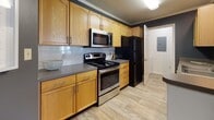 Located at 650 Bentley Ridge Blvd in Lancaster, PA, this single-floor residence offers a well-designed, open-concept layout that seamlessly connects the kitchen, dining, and living areas. The kitchen is equipped with warm honey-toned cabinetry, stainless steel appliances including a range and over-the-range microwave, a black refrigerator, tile backsplash, and dark countertops, all set atop durable wood-look flooring. A peninsula counter serves as a natural divider between the kitchen and the adjoining dining area, which features a bold navy accent wall that adds a striking visual contrast. Crown molding throughout the main living spaces lends a polished, finished look. The carpeted living room is generously sized, filled with natural light from large windows and a glass door, and opens to a comfortable, relaxed atmosphere. The bedrooms continue the navy accent wall theme, creating a cohesive and contemporary aesthetic. The primary bedroom is notable for its large windows that invite abundant natural light and direct access to a private bathroom. Additional rooms include a secondary bedroom, a full bathroom with wood-toned vanity and shower/tub combination, and a hallway with closet space. The overall ambiance is modern and inviting, with a consistent color palette of navy, neutral tones, and warm wood finishes throughout.