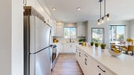 Located at 12115 State Ave in Marysville, WA, this well-appointed second-floor unit offers a thoughtfully designed single-level layout filled with natural light and contemporary finishes throughout. The kitchen is a standout feature, showcasing crisp white cabinetry, quartz countertops, a spacious island with pendant lighting, stainless steel appliances, and light-toned hardwood-style flooring — all framed by windows overlooking mature trees. The open-concept living and dining area is bright and welcoming, with large windows on multiple walls that invite abundant natural light and offer pleasant views of the surrounding neighborhood. The primary bedroom is a serene retreat with dual windows and clean, neutral tones. A secondary bedroom provides versatile space with a large window and hardwood-style flooring. Two bathrooms serve the unit — one featuring a tub-shower combination with modern matte black fixtures and a wide vanity, and another with a walk-in shower. A private balcony accessible from the living area extends the living space outdoors, offering open views of the community and the Pacific Northwest treeline under expansive skies. The unit combines modern design with functional comfort in a residential Marysville setting.