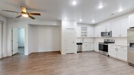 This well-appointed single-floor residence offers a clean, modern aesthetic throughout, anchored by warm wood-look flooring and crisp white walls that create a bright and cohesive atmosphere. The open-concept living and dining area is generously proportioned, featuring ceiling fans, recessed lighting, and large windows with access to an outdoor area, allowing natural light to flow freely through the space.

The kitchen is thoughtfully designed with white shaker-style cabinetry, light quartz countertops, a classic tile backsplash, and a full suite of stainless steel appliances including a French door refrigerator with ice maker, electric range with over-the-range microwave, and dishwasher. Open shelving adds a functional decorative touch, while ample cabinetry and a double-door pantry provide generous storage.

The primary bedroom is a serene retreat with a ceiling fan, soft natural light, and direct access to a spacious en-suite bathroom. The primary bath features large-format tile flooring, a dual-sink vanity with white cabinetry, a glass-enclosed shower, a soaking tub, and a walk-in closet with wire shelving. A secondary bedroom with a ceiling fan and window enjoys proximity to a full hallway bathroom, which mirrors the clean, white design found throughout the home.