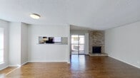 This single-floor residence offers a well-organized layout that balances open communal spaces with private quarters. The living area serves as the heart of the home, highlighted by a floor-to-ceiling brick fireplace that anchors the room with warmth and character. Wood-style flooring extends throughout the space, providing a cohesive and durable foundation. A pass-through window connects the living area to the kitchen, maintaining an open feel while defining each zone. Sliding glass doors lead to an outdoor balcony, drawing in natural light and providing a seamless indoor-outdoor connection.

The kitchen is equipped with ample white cabinetry, dark granite-style countertops, black appliances including a range and refrigerator, and a double sink — offering a practical and well-appointed cooking space. A dedicated hallway leads to the private areas of the home, where multiple bedrooms are found, each featuring wood-style flooring, ceiling fans with light fixtures, and windows that allow natural light to filter in. The bathrooms are clean and functional, featuring granite-style vanity countertops, tiled shower-tub combinations, and consistent flooring. Textured ceilings are present throughout, adding a classic residential finish to this thoughtfully laid-out home.