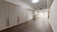 Located in the heart of Los Angeles, this modern studio unit at 1000 W 8th St offers a thoughtfully designed open-concept layout that seamlessly integrates the living, dining, and kitchen areas. Rich dark hardwood flooring runs throughout the main living space, complemented by clean white walls and recessed lighting that create a bright, contemporary atmosphere. Floor-to-ceiling windows provide city views and draw in natural light.

The kitchen is outfitted with sleek, light wood cabinetry paired with crisp white upper cabinets, dark granite countertops with a matching mosaic tile backsplash, and stainless steel appliances including a gas range and oven. A full-wall wood-paneled built-in closet system in the living area provides generous storage while maintaining the unit's streamlined aesthetic.

The bathroom is finished with large-format marble-look porcelain tile on both the walls and floors, lending a luxurious feel. A deep soaking tub with a granite surround and a frameless shower partition serve as standout features. Additional conveniences include a dedicated laundry area with a stacked Bosch washer and dryer, a pantry, and two closets, ensuring ample storage throughout this efficiently planned space.