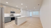 Located at 18300 E 51st Ave in Denver, Colorado, this modern 2-bedroom, 2-bathroom residence offers a thoughtfully designed single-level layout with clean, contemporary finishes throughout. The open-concept kitchen and living area serves as the heart of the home, featuring light wood-look flooring, recessed lighting, and large windows that invite abundant natural light. The kitchen is well-appointed with a central island with a white quartz countertop and undermount sink, a full suite of stainless steel appliances including a French door refrigerator, electric range, and built-in microwave, as well as a two-toned cabinet design combining light wood upper cabinets with dark lower cabinets and a white tile backsplash. The living area flows seamlessly from the kitchen, offering access to an exterior door and additional window views. Both bedrooms are generously sized and finished with plush neutral carpeting and ample natural light; the primary bedroom includes a ceiling fan. A second bedroom features light wood-look flooring. Each bathroom is finished in a clean, minimal style with white countertops, undermount sinks, and chrome fixtures. Two dedicated closets provide practical storage. The overall aesthetic is bright, airy, and move-in ready.