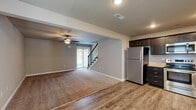 Located at 1750 Emily Lane in Belton, Missouri, this two-story home offers generous living space across its main and upper floors. The open-concept kitchen and living room serve as the heart of the home, featuring dark espresso cabinetry, granite-look countertops, stainless steel appliances including a refrigerator, range, microwave, and dishwasher, and durable wood-look flooring. The living area flows seamlessly from the kitchen, with plush carpeting, a ceiling fan, and a sliding glass door that brings in natural light and provides outdoor access. A staircase with wood treads and metal balusters connects the floors. The home includes four bedrooms, several featuring vaulted or elevated ceilings, ceiling fans, and carpet flooring. The primary bedroom is well-sized with its own dedicated space and closet. Additional bedrooms each offer built-in closets and natural light through blinded windows. Three bathrooms are finished with wood-look flooring and granite-topped vanities; one includes a walk-in shower with sliding glass doors, while another features a full tub-shower combo. The property also boasts a sizable, open outdoor area with lush green grounds, visible from the 3D overview.