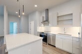 Located at 305 Winter St in Waltham, MA, this well-appointed 2-bedroom, 2-bathroom residence offers a thoughtfully designed open-concept layout with modern finishes throughout. The kitchen serves as a focal point, boasting flat-front white cabinetry extending to the ceiling, quartz countertops, a subway tile backsplash, and a full suite of stainless steel appliances including a gas range with a stainless hood, dishwasher, and a side-by-side refrigerator. A large central island provides additional prep space and seating, while stylish pendant lighting adds a contemporary touch. Light wood-tone flooring flows through the main living areas, complementing the clean, neutral color palette. Both bathrooms feature glass-enclosed walk-in showers with detailed tile work, modern vanities with white countertops, and wood-look flooring. The bedrooms are comfortably sized, with plush carpeting and windows that invite natural light and offer views of the surrounding landscape. The primary bedroom includes access to a dedicated closet. Two closets provide practical storage solutions throughout the unit. The overall ambiance is clean, bright, and modern, making this an attractive residence in the heart of Waltham.