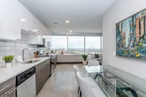 Located in the heart of Kansas City, MO, this well-appointed single-floor residence at 201 W Sixth St offers a thoughtfully designed layout that balances comfort and modern aesthetics. The open-concept living and dining area serves as the centerpiece of the space, featuring warm neutral tones, polished concrete-style flooring, and recessed lighting throughout. Vibrant, multicolored area rugs and contemporary artwork add a lively, curated character to the living area, which is furnished with a plush sofa, accent chairs, and a sleek coffee table.

The kitchen is outfitted with stainless steel appliances — including a full-size refrigerator, dishwasher, microwave, and range — complemented by two-tone cabinetry featuring white upper cabinets and wood-grain lower cabinets, a classic white subway tile backsplash, and light countertops. The layout flows seamlessly into the dining area, which accommodates a table and chairs ideal for everyday meals.

The bedroom is a calm retreat with warm gray walls, a ceiling fan with lighting, a spacious closet with sliding doors, and a full-length mirror. A private bathroom features a glass-enclosed walk-in shower, open shelving for storage, and clean, neutral finishes. The overall ambiance of the space is contemporary, functional, and inviting — well-suited for urban living in downtown Kansas City.