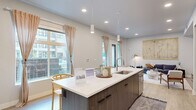 This thoughtfully designed single-floor residence showcases a clean, contemporary aesthetic throughout its open and well-connected layout. The kitchen serves as a central hub, anchored by a large island with a white quartz countertop, an undermount sink, and seating for multiple guests. Two-tone cabinetry — combining dark wood lower cabinets with crisp white upper cabinets — pairs seamlessly with a full suite of stainless steel appliances, including a side-by-side refrigerator, range, and built-in microwave. Pendant lighting above the island and recessed ceiling lights ensure ample illumination, while large windows flood the space with natural light and offer views of the surrounding neighborhood.

The open-concept living area flows directly from the kitchen, featuring light wood-look flooring, recessed lighting, and a wall-mounted flat-screen TV. A set of French doors opens to a private balcony, extending the living space outdoors. The bedroom is a tranquil retreat, carpeted for comfort and bathed in natural light from a generous window. The bathroom features a large vanity with white quartz countertop, an undermount sink, and contemporary fixtures, completing this well-appointed residence.
