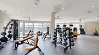 Located at 601 W Bacon St in Richmond, Virginia, this fitness center offers a spacious, single-floor layout designed to accommodate a comprehensive range of workout activities. The open floor plan is finished with durable rubber flooring throughout, providing a safe and functional surface suited for both strength training and cardio exercise.

The facility is generously equipped with a wide selection of premium Hoist-brand strength machines, including cable cross systems, plate-loaded machines, and multi-function cable stations. A full rack of dumbbells and multiple adjustable benches provide ample options for free weight training. Cardio equipment, including treadmills and a rowing machine, rounds out the offering for full-body fitness routines.

Architecturally, the space features a curved wall of large floor-to-ceiling windows that flood the interior with natural light and frame views of the surrounding Richmond neighborhood. Recessed lighting and multiple ceiling fans ensure the space remains bright, comfortable, and well-ventilated. Structural columns with clean white trim add a classic design element while defining distinct workout zones within the open layout.

The overall ambiance is modern, bright, and professional, creating an inviting environment well-suited for daily fitness routines.