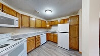 Located at 1555 118th Ln NW in Coon Rapids, Minnesota, this one-bedroom, one-bathroom unit offers a practical and well-organized single-floor layout. The open-concept living, dining, and kitchen area forms the heart of the unit, providing a cohesive space for daily living. The kitchen is well-equipped with warm oak cabinetry, granite-style laminate countertops, and a full suite of white appliances including a range, over-the-range microwave, dishwasher, and refrigerator. Light-toned vinyl plank flooring runs throughout the main living areas, adding durability and a clean aesthetic. The living area features neutral walls, baseboard heating, and a window that brings in natural light. The bedroom is carpeted for comfort, offering a ceiling fan with light fixture, a set of bi-fold closet doors, and a window overlooking the outdoors. A second window in the bedroom provides additional natural light. The bathroom is thoughtfully outfitted with a full soaking tub and shower combo featuring stainless steel grab bars for accessibility, a vanity with storage, and an overhead cabinet. Three closets throughout the unit offer generous storage. Textured ceilings and warm wood trim are consistent throughout, lending a cohesive, classic character to the space.