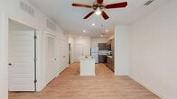 Located in South Fulton, GA, this single-story one-bedroom, one-bathroom unit offers a well-designed layout with modern finishes throughout. The open-concept living and kitchen area is anchored by a central island with light stone-look countertops and a built-in sink, providing both prep space and a casual gathering spot. The kitchen is equipped with stainless steel appliances—including a refrigerator, electric range, and over-the-range microwave—complemented by warm taupe shaker-style cabinetry, a classic subway tile backsplash, and recessed lighting. Light wood-style flooring runs consistently throughout the main areas, enhancing the sense of openness. A ceiling fan with integrated lighting serves both the living area and the bedroom, which features a large window that invites natural light and outdoor views. The bedroom connects to a spacious walk-in closet outfitted with multi-tier wire shelving for ample storage, plus an additional closet nearby. The full bathroom includes a single-sink vanity with dark cabinetry, a tub/shower combination, and tile flooring. Additional conveniences include a dedicated laundry area and a utility room, rounding out this efficiently organized and move-in-ready space.
