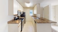 This single-floor 1-bedroom, 1-bathroom residence offers a practical and comfortable layout designed to maximize every square foot of living space. The galley-style kitchen is efficiently organized with ample white cabinetry extending to the ceiling for generous storage, granite-style laminate countertops, and a full suite of stainless steel appliances including an electric range, microwave, refrigerator, and dishwasher. Light tile flooring and a window at the end of the kitchen bring in natural light, creating a bright and functional cooking space. The living area features carpeted flooring, a fireplace, and windows dressed with vertical blinds that allow for adjustable natural light. The bedroom is a well-sized, carpeted room with a large window featuring vertical blinds and a baseboard heating unit, offering a quiet and comfortable retreat. The bathroom is cleanly finished with a white vanity cabinet, granite-style countertop, an undermount sink, and a lighted mirror above. A separate mirror panel and a shower complete the space. Throughout the unit, the neutral warm tones and consistent finishes create a cohesive, move-in-ready ambiance.