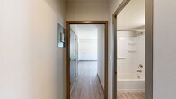Located at 707 W Fifth Ave in Spokane, Washington, this one-bedroom, one-bathroom unit offers a thoughtfully organized single-floor layout. Light wood-style flooring runs throughout, creating a clean and cohesive aesthetic across every room.

The combined kitchen and living area forms the heart of the unit. The kitchen is well-appointed with rich dark wood cabinetry, light countertops, stainless steel appliances including a gas range, microwave, and refrigerator, and a stacked in-unit washer and dryer tucked neatly into a dedicated alcove. A window provides natural light to the kitchen space. The adjacent living area is open and bright, with multiple windows offering views of the surrounding Spokane cityscape and allowing natural light to fill the room.

The bedroom is a comfortable, well-proportioned space featuring a large window with city views, light-toned walls, and the same wood-style flooring found throughout the unit. A closet provides dedicated storage.

A hallway connects the main living spaces to the bathroom, which features a full soaking tub and shower combination with built-in shelving, a wall-mounted sink, and a mirrored medicine cabinet. The unit also includes a dedicated hallway closet for additional storage. Gray-toned door and window trim adds a modern finishing touch throughout.