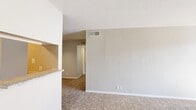 This single-story, 2-bedroom, 1-bathroom home offers a practical and comfortable floor plan designed for efficient everyday living. The combined living and dining area serves as the heart of the home, featuring plush wall-to-wall carpeting, neutral toned walls, and a tile-surround fireplace that adds a welcoming focal point. A sliding glass door floods the living space with natural light, complemented by vertical blinds for adjustable privacy.

The galley-style kitchen is thoughtfully equipped with gray cabinetry, white countertops, a built-in sink, and black appliances including a refrigerator and range. Light wood-look flooring runs throughout the kitchen, adding warmth and easy maintenance underfoot.

Both bedrooms are carpeted and feature neutral walls that provide a calm, restful atmosphere. The primary bedroom includes a ceiling fan and direct access to the shared bathroom and a dedicated walk-in closet outfitted with multiple shelving units and hanging rods for ample storage. The second bedroom benefits from natural light through a slatted window with blinds.

The full bathroom includes a single-sink vanity with gray cabinetry, a large mirror, a tub-shower combination with white tile surround, and light wood-look flooring. Additional conveniences include an in-unit laundry area, completing this functional and move-in-ready home.