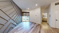 Located at 5655 Pershing Ave in St. Louis, Missouri, this single-floor unit offers a compelling blend of modern design and functional living. The open-concept layout is anchored by wide-plank wood-look flooring that flows seamlessly through the main living areas, complemented by recessed lighting and clean white walls that create a bright, airy atmosphere.

The kitchen is a true standout, showcasing floor-to-ceiling wood-toned cabinetry, a striking marble-look tile backsplash, and a central island with an illuminated base and crisp white quartz countertop. Stainless steel appliances, including a smart refrigerator and black range, add a sophisticated edge, while a sculptural multi-globe pendant light overhead adds an artistic focal point.

The living area features a bold geometric accent wall with angular paneling, adding dramatic visual interest, along with sliding glass doors that invite natural light and provide outdoor access. The bedroom is carpeted for comfort and includes a window with a roller shade.

The bathroom is elegantly appointed with dark hexagonal floor tile, a double-sink vanity with wood cabinetry and a white countertop, matte black fixtures, and a walk-in glass shower enveloped in full-height marble-look tile with a rain showerhead — a refined, spa-inspired retreat.