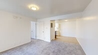 This single-floor unit offers a bright, well-organized layout designed for comfortable everyday living. The main living area features soft wall-to-wall carpeting, smooth white walls, and flush-mount ceiling lighting, creating a clean and neutral aesthetic throughout. Two interior doors provide access to additional rooms and closet storage, while an open passage leads into the adjacent kitchen and extended living space with light hardwood-style flooring.

The kitchen is efficiently designed in a galley configuration, featuring white cabinetry, light countertops, a stainless steel sink, a range with hood ventilation, and a stainless steel refrigerator. A skylight overhead fills the space with natural light, enhancing the clean, functional atmosphere.

The bedrooms are carpeted and offer a calm, versatile space. One bedroom benefits from a sliding glass door that opens to a private balcony, providing outdoor access and natural light. Another bedroom features a window with views of the surrounding neighborhood.

The bathroom is neatly appointed with light hardwood-style flooring, a white vanity with ample counter space, a toilet, and a full tub-shower combination with a curtain rod. The overall design of this unit emphasizes a clean, move-in-ready aesthetic with a consistent palette of whites and neutrals throughout.