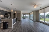 Located at 777 Hemlock St in Macon, Georgia, this single-floor unit offers a thoughtfully designed open-concept layout filled with natural light. The expansive living area is lined with floor-to-ceiling windows and fitted with a ceiling fan, providing sweeping views of the surrounding Macon cityscape and greenery. Light-toned wood-look flooring flows seamlessly throughout the space, lending a clean and cohesive aesthetic.

The kitchen is a standout feature, anchored by a large center island with granite countertops and a built-in sink with pendant lighting above. Gray shaker-style cabinetry reaches to the ceiling, complemented by a classic white subway tile backsplash and a full suite of stainless steel appliances, including a refrigerator with ice maker, electric range, and microwave. A pantry closet adds to the kitchen's functionality.

The bedrooms are generously proportioned, each benefiting from large windows with roller shades and ceiling fans that maximize comfort and natural light. The bathroom is well-appointed with teal-toned cabinetry, granite countertops, a wide vanity mirror, and wood-look tile flooring. A second bathroom offers a similarly refined finish. The overall ambiance is modern, bright, and move-in ready.